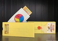 Yellow vintage Fisher Price toy film camera with two toy film cassettes, one marked Sesame Street and the other unmarked.