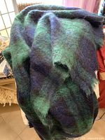 Image showing the full blanket draped, highlighting the green and navy plaid wool fabric texture.
