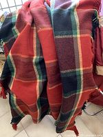 Red plaid wool blanket draped showing color and fringe detail.