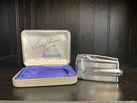 Photo showing vintage silver-tone Ronson Varaflame lighter next to original textured case with satin and velvet lining and Ronson branding inside case lid.