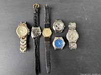 Six vintage men's wristwatches arranged on black surface, showing variety of styles and bands.