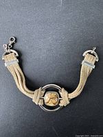 Full view of the sterling silver bracelet featuring beige suede straps and a lobster clasp