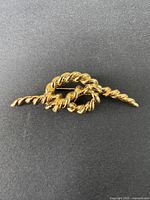 Gold tone twisted rope brooch on a black background showing full front view