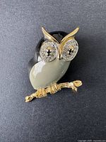 Front view of vintage D'ORLAN owl brooch showing rhinestone eyes and enamel body on black background.
