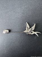 Close-up of the silver dove brooch showing details of wings and body on black background