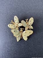 Brooch showing three enamel and gold-tone butterflies on dark background.