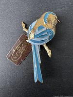 Front view of the vintage D'ORLAN sparrow brooch with blue enamel wings, tail, and head details, showing gold-toned textured feathers and rhinestone eye.