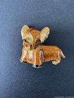Brooch angled on a black surface showing detailed enamel finish and dog design.