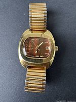 Front view of vintage gold-tone Sheffield automatic wristwatch showing dial, hands, date window, and branding.