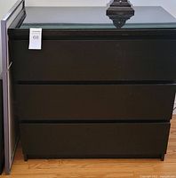 Front view of black 3 drawer dresser with mint condition and label '68'.