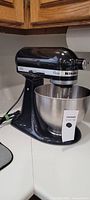 Front side view of black KitchenAid Classic stand mixer with stainless steel bowl.