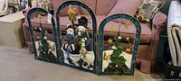 Full view of three-panel metal fireplace gate with Christmas scenes: snowmen, trees, stars and villages