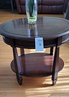 Full view of round wooden occasional table showing legs and lower shelf