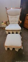 Full view of maple rocking chair with cream fabric upholstery and matching ottoman, showing overall condition and style.