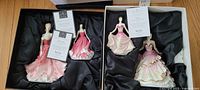 Two boxes each containing two Royal Doulton Pretty Ladies figurines with certificates in black satin lining.