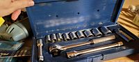 Blue metal socket wrench set with ratchet handle, sockets, and extensions in metal case