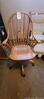 Front view of a vintage oak office chair showing curved spindle backrest and contoured seat.