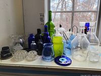 Entire lot of colored glass items placed on windowsill showing diverse shapes and colors
