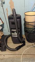 Full view of grey canister vacuum with attached hose, wand, and floor nozzle