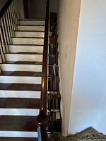 Photo of vintage books stacked along narrow space beside staircase showing the mixture of old volumes with worn and weathered covers and spines.
