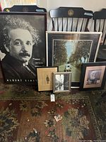 Group photo showing 6 framed vintage prints leaning on chairs: large Albert Einstein poster, varied framed photographic and graphic prints