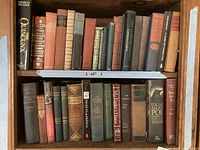 Full view of two bookshelves containing a collection of vintage hardcover books of various classic authors and titles.