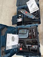 Overview image showing Bosch oscillating saw in black and gray with red buttons, with accompanying user manual inside a black carrying case. Below it is a Bosch laser level set with blue carrying case containing laser level, pouch, batteries, and accessories.