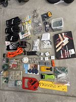 Overview of household utility items including work gloves, fasteners, picture hanging supplies, caulk tool kit, light bulb, multi outlet plugs, 90 degree squares, twine, carabiners, keychain rings, and surface protection kit.