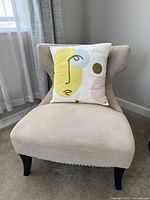 Full view of the light beige accent chair with throw pillow on seat, showing fabric condition and shape.
