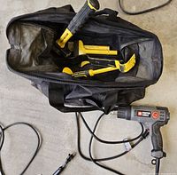 Porter Cable heat gun near black tool bag holding Stanley hand tools on a concrete floor