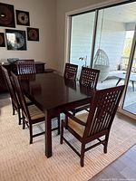 Full dining set with table, eight chairs arranged on rug near sliding glass doors