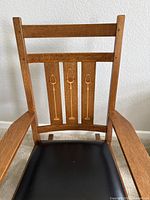Close-up of chair back and seat showing wood grain and leather upholstery