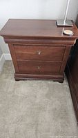 Front view of Thomasville end table showing medium brown wood finish and two main drawers with brass keyhole hardware.