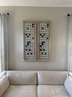 Full view of two shadow boxes mounted on wall with beige couch below.