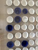 Close-up of ceramic cups with white and royal blue glaze inside shadow box