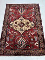 Full view of the Sarab rug displaying rich red background with beige central medallion and layered floral and geometric border patterns.