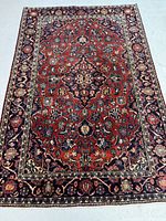 Full view of red Kashan rug with central medallion and navy-cream border