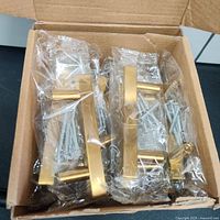 Box of 15 gold metal cabinet or drawer handles individually bagged with screws.