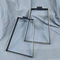 Pair of solid steel rectangular furniture legs with a satin black finish laid on blue cloth background.