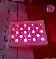 Red and infrared LEDs lit up on the therapy panel showing 40 individual LED lenses glowing red and white light.