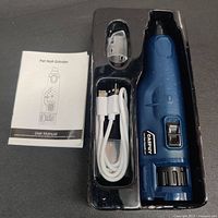 Opened packaging showing the Casfuy pet nail grinder in blue, with USB charging cable, protective cover, and user manual.