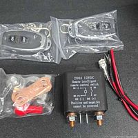 Full lot laid out, showing two remote key fobs in plastic bags, remote intelligent switch with wiring diagram text, wiring cables and hardware components.