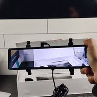 12 inch rear view mirror showing digital screen in operation held in hand with open box underneath.