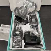 Top view of the two walkie talkies still in plastic casing inside the box, with charging stations and wired earbuds also visible.