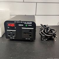 Front and side view of Yinleader voltage converter showing power switch, indicator light, voltage input and output sockets, and power cord.