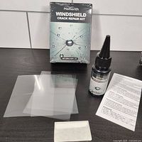 Front view of kit contents including repair resin bottle, curing strips, white patch, instructions, and box packaging.