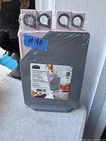 Photo of four new-in-box Mainstays cutting boards stacked together with packaging visible showing they are plastic and have color-coded labels for different uses.