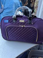 Front view showing the purple quilted pocket, Kensie logo, and handles wrapped in plastic.