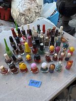 Wide view of 44 assorted nail polish bottles arranged on an outdoor surface, showing typical packaging and colors with some used items.