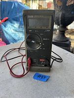 Front view of Fluke 77 multimeter showing screen, rotary dial, and attached test probes.